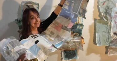 A woman holds a long roll of different pieces of paper glued together.