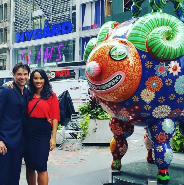 Photo of Emmanuel and Mary in front of one of their artist's work