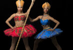 Two constumed dancers, one in a red costume and the other in blue