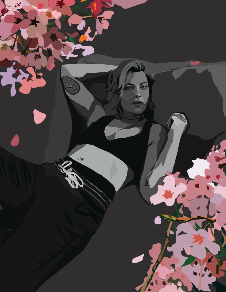 black and white image of a woman lying on the ground, wearing jogging pants and sports bra, with pink blossoms on two opposite corners.  