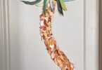 A wavy palm tree on paper with a blue bird flying above it, all hung on a door