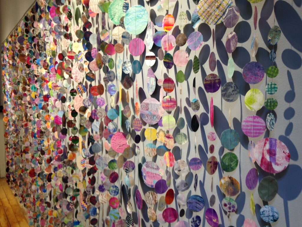 Installation of 2000 mixed media paper circles sewn together creating a curtain