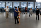Photograph of a couple dancing with people looking on.