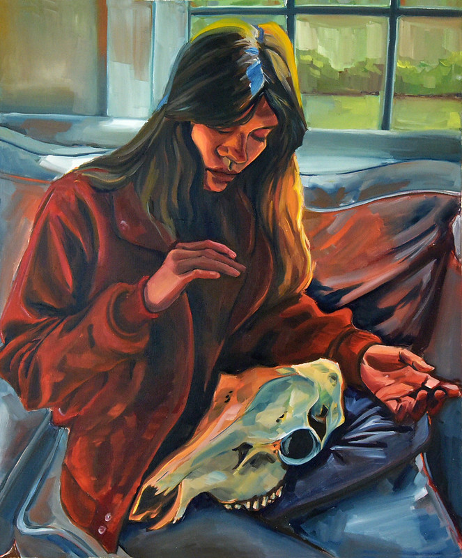 a girl is seated o a sofa with one leg crossed under her.  She is wearing a rust colored jacked and cradling a steer scull on her lap. There is a window behind her overlooking a garden.  
