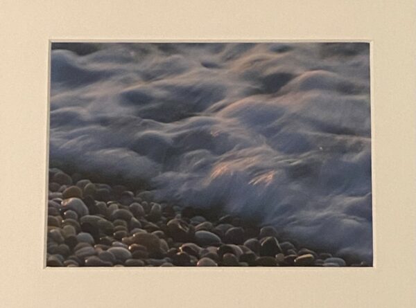 color photograph of foaming waves on a pebble beach
